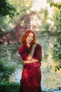Red-haired woman posing in autumn park by water