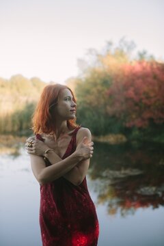 Woman with red hair enjoying autumn nature reflecting in water