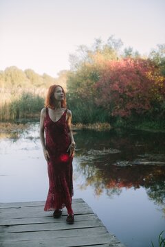 Woman with red hair standing on autumn lake dock