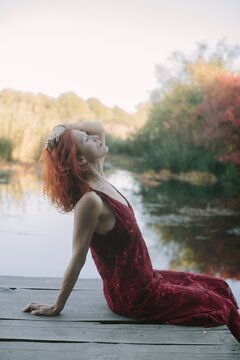 Woman with red hair relaxing by a lake