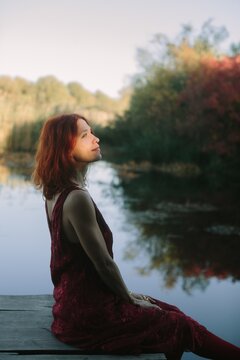 Woman enjoying peaceful autumn sunset on lake dock