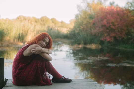 Red haired woman enjoying peaceful autumn moment by lake
