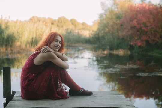 Woman with red hair relaxing on autumn dock
