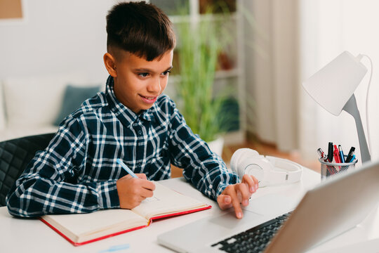 Young boy learning online and doing homework with laptop
