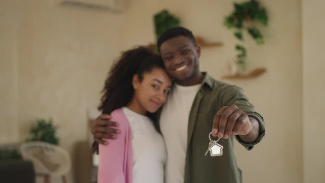 Portrait of young Black couple showing house key and smiling, new home purchase