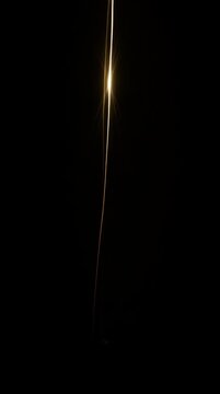 Abstract motion graphics video of glowing golden light streaks and laser lines gracefully crossing and moving vertically against a pure solid black background. Bright optical lens flares, smooth fluid