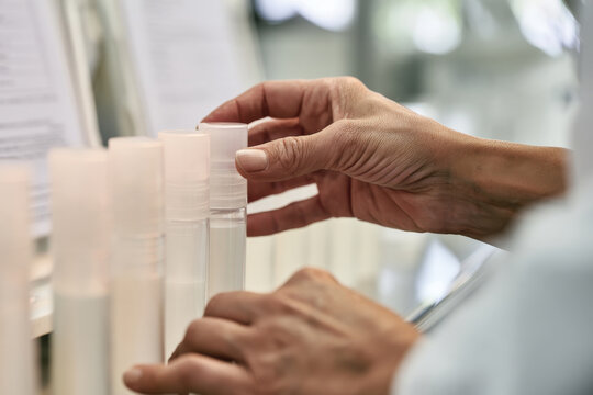 This image captures hands meticulously fine-tuning the arrangement of transparent cosmetic bottles, highlighting precision and care in branding and visual presentation.