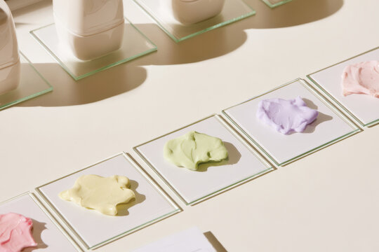 A vibrant display of colorful creams on glass plates for skincare testing, showcasing the diversity of skincare formulations and artistry in product design and selection.