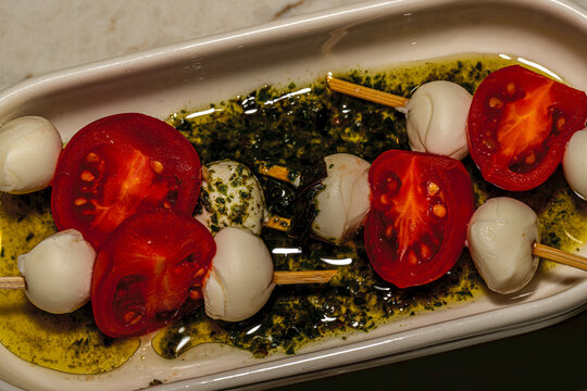 Rustic Mediterranean appetizer: extra virgin olive oil dipping plate with cherry tomatoes, mozzarella cheese balls, and fresh bread.
