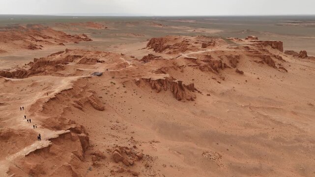 High angle drone perspective of rugged red clay formations, steep ridges, and wind-sculpted badlands at the Flaming Cliffs in the Gobi Desert, Mongolia tourist walking path
