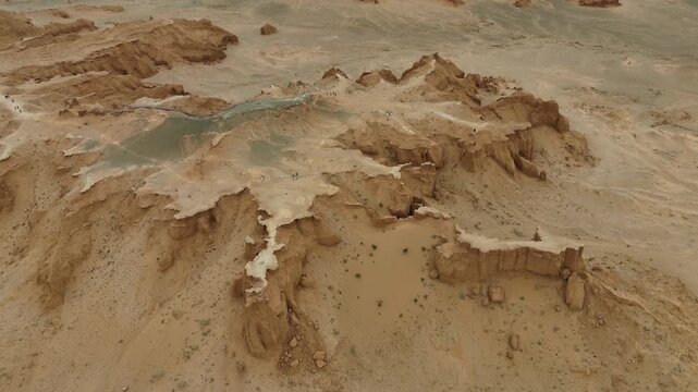 aerial drone shot revealing intricate wind-carved red sandstone escarpments and fossil-rich ravines across the arid expanse of the Flaming Cliffs in the Gobi Desert, Mongolia