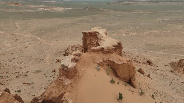 drone approach the iconic red sandstone cliffs structure and rugged badlands of the Flaming Cliffs in the Gobi Desert