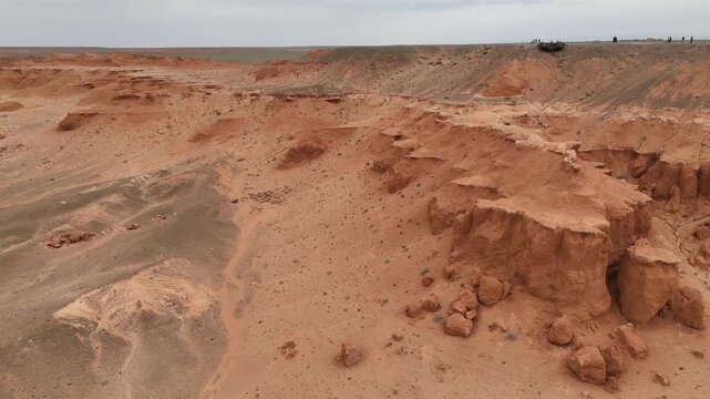 Cinematic aerial drone view of the iconic red sandstone formations and eroded canyons of the Flaming Cliffs during an expedition across the Gobi Desert, Mongolia