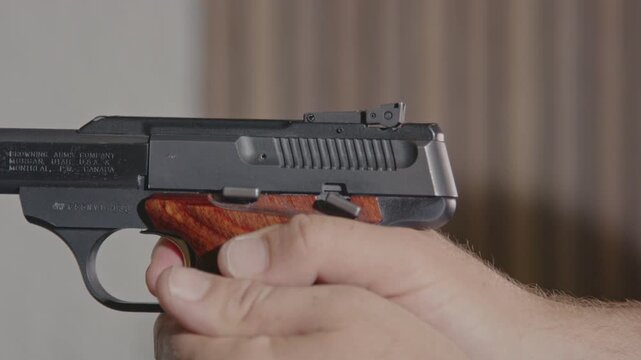 Close up of a small caliber pistol being fired on a shooting range, the slide stays open while an empty casing gets ejected in slow motion