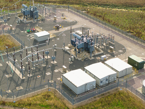 Aerial view of Braybrook substation 400kV featuring electrical transformers, switchgear, and utility buildings within a secure perimeter fence, Market Harborough, England, United Kingdom.