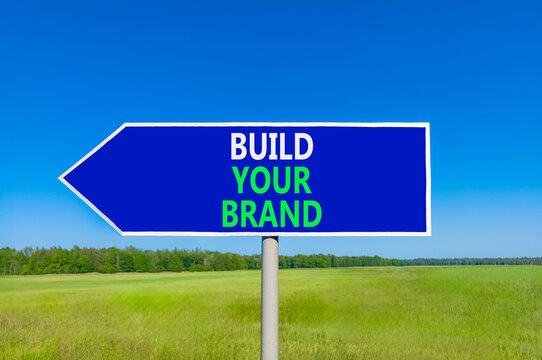 Build your brand words symbol. Concept words Build your brand on beautiful blue road sign. Beautiful blue sky green grass background. Business and build your brand concept. Copy space.