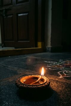 Illuminated Earthen Diya with Rangoli Pattern on Floor During Festival of Lights