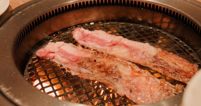 網の上でトングを使って香ばしく焼き上げる大判の牛カルビ肉