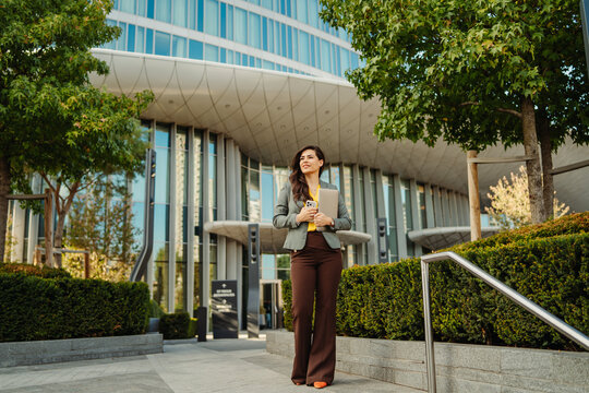 Businesswoman walking confident in front of a corporate skyscraper