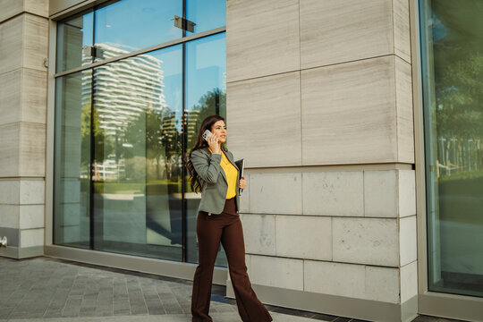 Businesswoman walking and talking on cell phone outside office