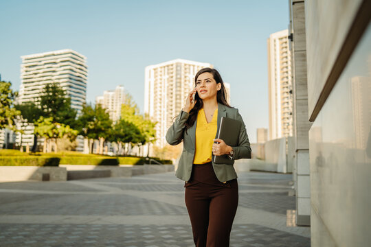 Businesswoman walking outdoors while talking on phone