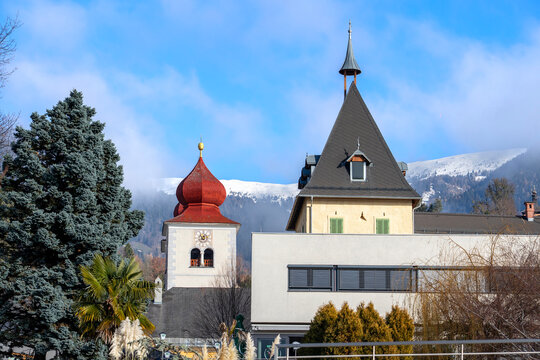 Historic church towers with snow covered Alpine mountains in winter