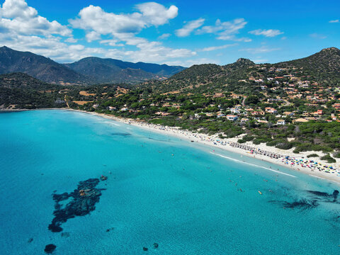 Aerial view of Campulongu beach with white sand, turquoise sea, villas and mountains in the background, Villasimius, Sardinia, Italy