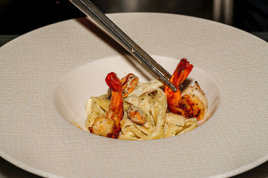Classic Italian seafood pasta: shrimp fettuccine pasta served with creamy garlic sauce and fresh parsley on a plate.