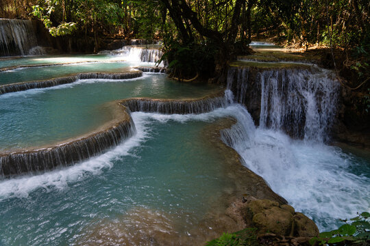 Aerial view of Kuang Si Waterfall with turquoise tiered pools and cascading waterfalls surrounded by lush tropical jungle in Luang Prabang, Luang Prabang Province, Laos.