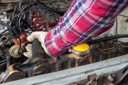 Horizontal stock photo of mechanic inspecting radiator hose in car engine bay