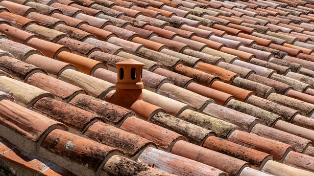 Traditional mediterranean roof with terracotta colored barrel or clay tiles and a ventilation pipe