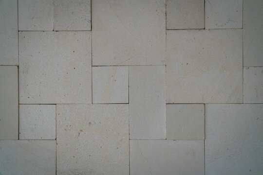 Light beige rectangular stone tiles arranged in an irregular geometric wall pattern, with subtle surface variations and thin dark joints.