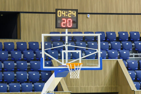 Basketball Hoop with Shot Clock and Scoreboard Timer in Empty Indoor Arena with Blue Stadium Seats