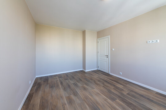 Laminated wood floor with white wall. Empty room with floating laminate in new apartment. Home renovation and real estate background.