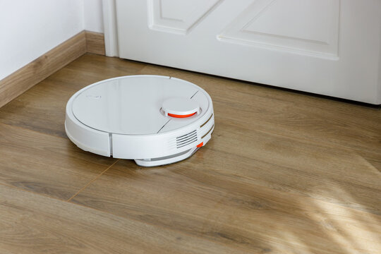 Vacuum Robot cleaning at home. Robot vacuum cleaner in the modern home. Smart cleaning technologyVacuum Robot cleaning at home. Robot vacuum cleaner in the modern home. Smart cleaning technology