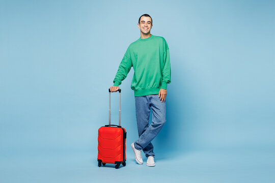 Traveler happy man wear shirt casual clothes hold suitcase bag looking camera isolated on plain blue background. Tourist travel abroad in free spare time rest getaway Air flight trip journey concept.