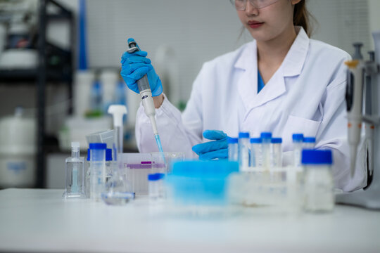 Female scientist performing laboratory experiment with pipette and test tubes