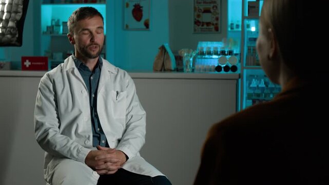 Middle aged Caucasian male pharmacist talking to reporter during interview in pharmacy store, over shoulder view. Suitable for healthcare advertising and medical campaigns