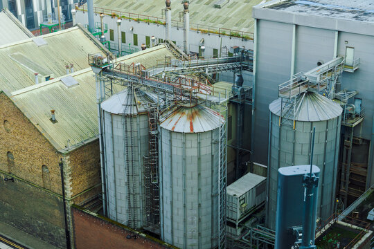 View of industrial metal silos and storage tanks at a facility with surrounding brick and metal buildings in Dublin, County Dublin, Ireland.
