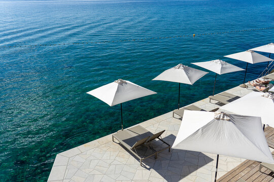 Seaside terrace with umbrellas and loungers overlooking calm blue ocean water Opatija Croatia