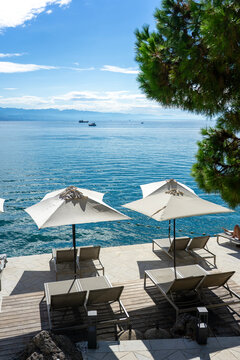Seaside terrace with umbrellas and loungers overlooking calm blue ocean water Opatija Croatia