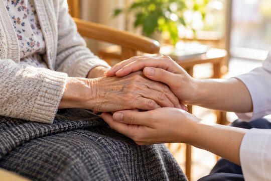 Caregiver Gently Holding Elderly Person's Hands in a Warm Japanese Home Care Setting