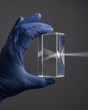 Gloved Hand Holding a Glass Prism with Light Beam