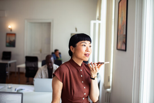 Businesswoman using voice command on smartphone in office