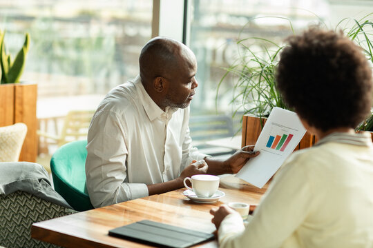 Man presenting bar chart during cafe meeting