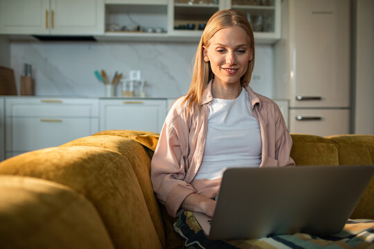 Smiling woman using laptop on sofa at home