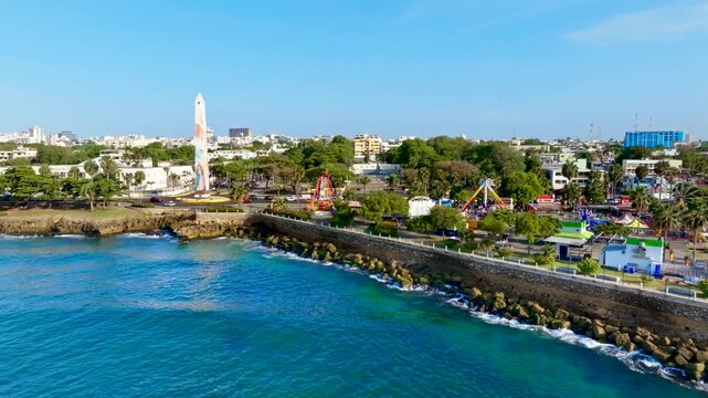 A view from the sea of ​​a high-speed highway along the ocean coast. A coastal city on a sunny summer day. Amusement park on the coast. An obelisk. Santo Domingo, Dominican Republic &ndash; August 26, 2026.