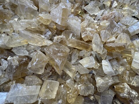 Full frame background texture of raw yellow calcite (honey calcite) mineral crystals with rhombohedral cleavage. Ideal for geology, gemstone, crystal healing, mineralogy, and natural background design