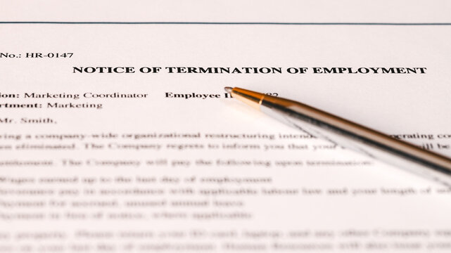 Notice of termination of employment document with a pen on desk. Job layoff, contract cancellation, workforce reduction, corporate firing, and employment dismissal concept