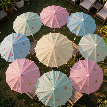 Outdoor event planning and garden party decor, colorful paper parasols arranged in a circle over patio furniture in a backyard setting at sunset